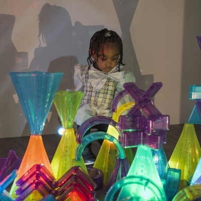 Criança observa brinquedos de construção coloridos e transparentes