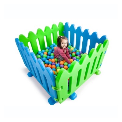 Parque infantil plástico azul e verde cheio de bolas coloridas com menina dentro.