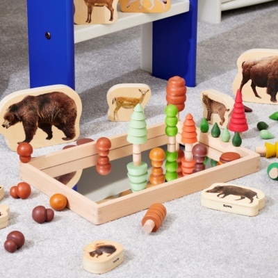 Brinquedos de madeira coloridos com figuras de animais e base espelhada no chão