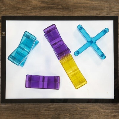 Pegadores plásticos translúcidos em azul, roxo e amarelo sobre superfície branca com moldura preta