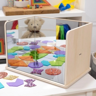 Espelho de mesa com formas geométricas coloridas refletidas, em ambiente infantil