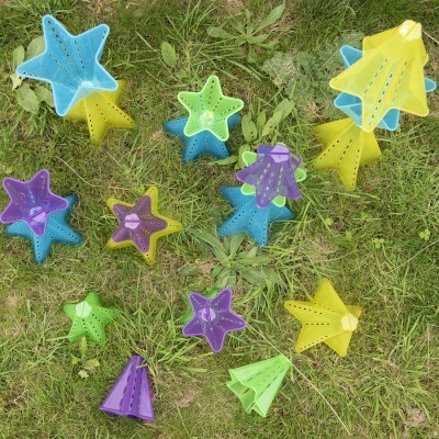 Brinquedos de areia coloridos em forma de estrelas e cones sobre relva