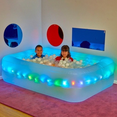 Piscina insuflável com luzes LED e bolas plásticas em quarto com espelhos