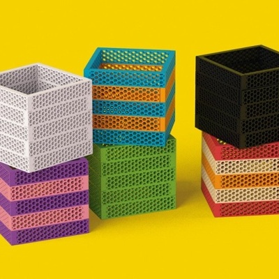 Caixas quadradas de plástico perfurado coloridas empilhadas sobre fundo amarelo