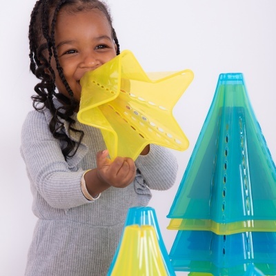Menina a brincar com estrela amarela e cones de plástico verdes e azuis