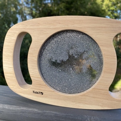Objeto de madeira com líquido e bolhas no centro, marca TickiT