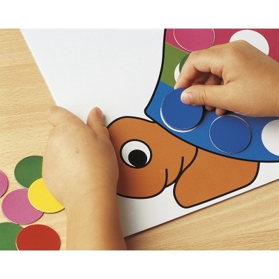 Mãos infantis a colocar peças redondas coloridas num tabuleiro com desenho de polvo.