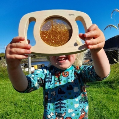 Criança segura objeto de madeira com glitter dourado no exterior