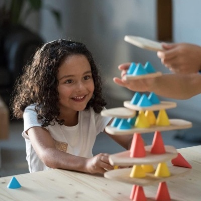Brinquedo de madeira com cones coloridos empilhados formando uma torre com criança a jogar
