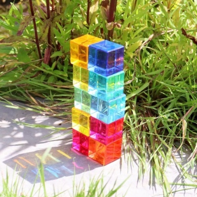 Cubos translúcidos coloridos empilhados com sombra colorida e relva ao fundo