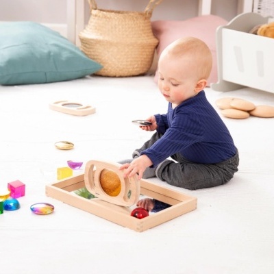 Bebé a brincar com brinquedo de madeira com pedras coloridas num quarto