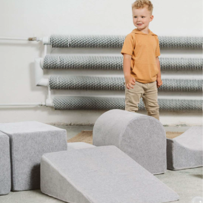 Peças macias cinza para crianças e menino em fundo com radiadores