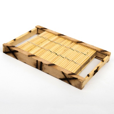 Tabuleiro retangular de madeira clara com superfície de palhinhas de bambu