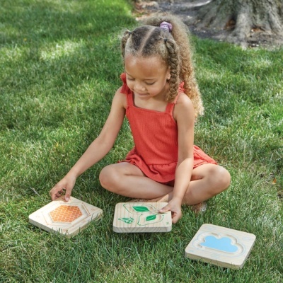 Criança brincando com peças de madeira na relva