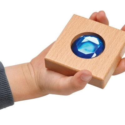 Mãos segurando cubo de madeira com cristal azul