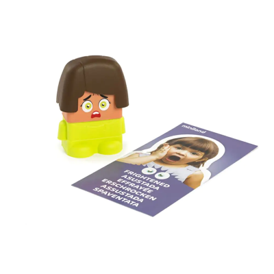 Boneco de cabeça com cabelo castanho e expressão assustada junto a cartão com texto multilingue.