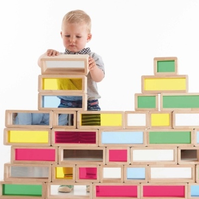 Criança a empilhar blocos coloridos e espelhados de madeira