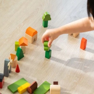 Blocos de madeira coloridos e mão de criança num chão claro