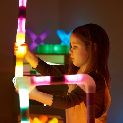 Menina a brincar com tubos luminosos de plástico colorido