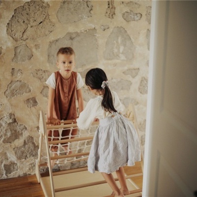 Duas crianças brincando com brinquedo de madeira em parede de pedra