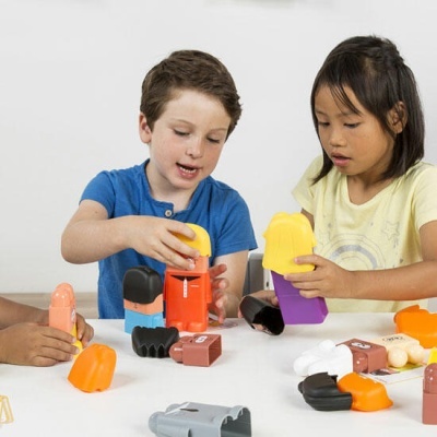 Crianças a brincar com peças de brinquedo coloridas sobre mesa branca