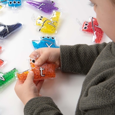 Bolsa de gel laranja em forma de avião com letra 't' segurada por criança