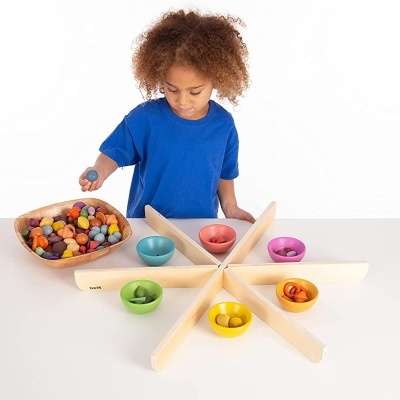 Criança a jogar com brinquedo de madeira colorido com tigelas e peças pequenas.