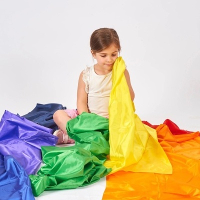 Criança com tecido colorido em cores do arco-íris no chão branco