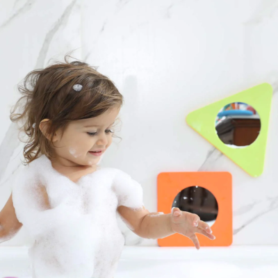 Criança em banheira com espuma e formas geométricas coloridas na parede