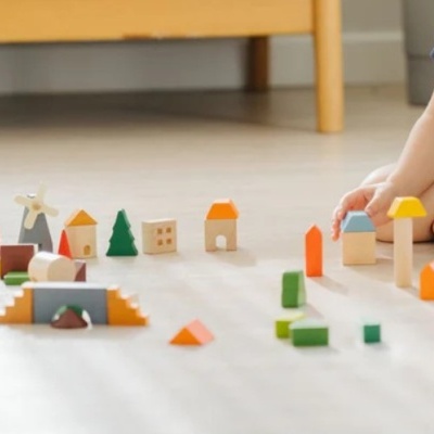 Blocos de construção em madeira coloridos no chão com mão de criança