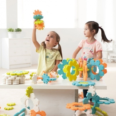 Duas meninas a brincar com peças de construção de plástico coloridas sobre uma mesa