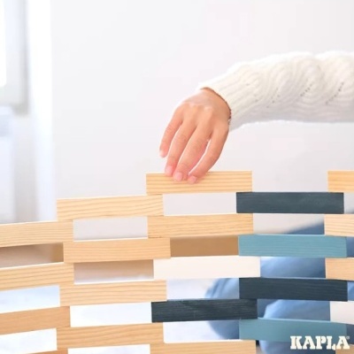 Criança a empilhar blocos de madeira coloridos da marca KAPLA