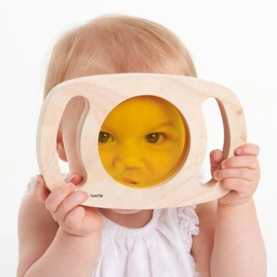 Brinquedo de madeira com lente amarela segurado por criança pequena