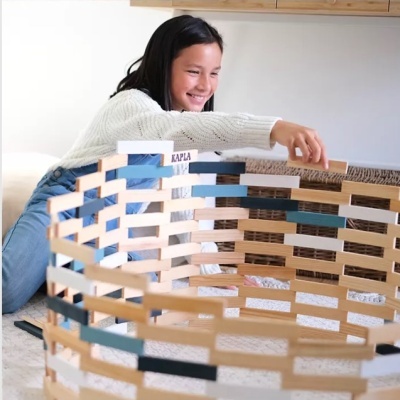 Menina a brincar com blocos de madeira coloridos montados em círculo no interior