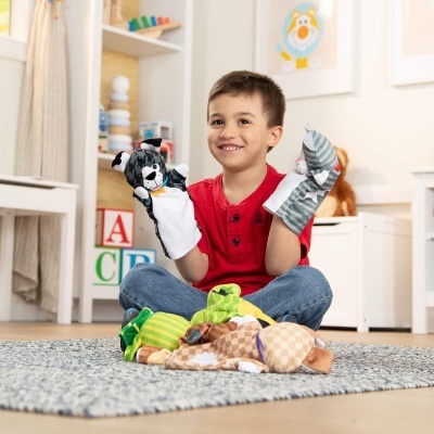 Menino sentado no chão com meias peúgas de animais em sala decorada