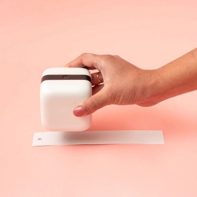 Carimbo quadrado branco com faixa castanha escura carimbando uma tira de papel branca