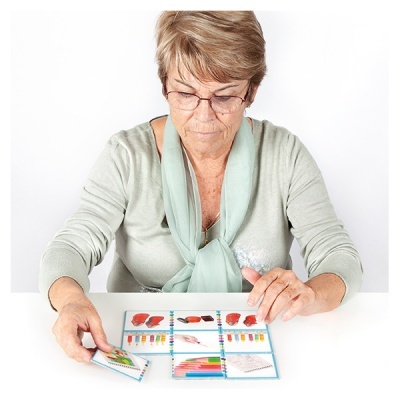 Mulher idosa organizando cartas coloridas numa mesa branca
