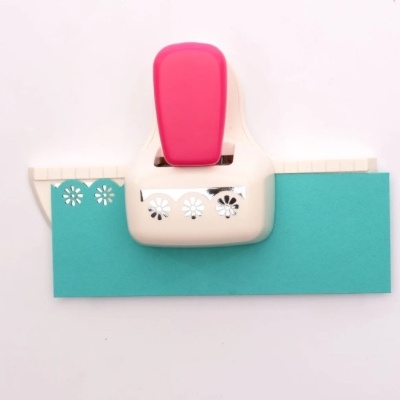 Furador manual branco e rosa com papel azul perfurado