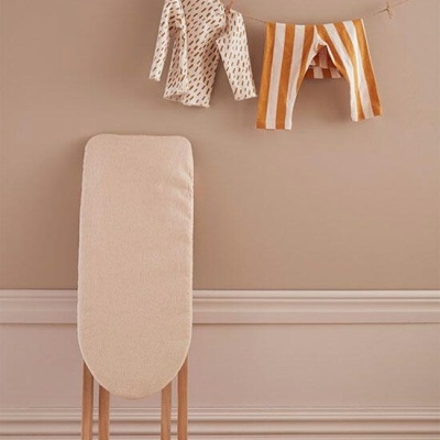 Tábua de passar roupa com roupas infantis penduradas numa linha e meias ao chão