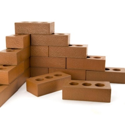 Tijolos castanhos com quatro furos empilhados sobre fundo branco