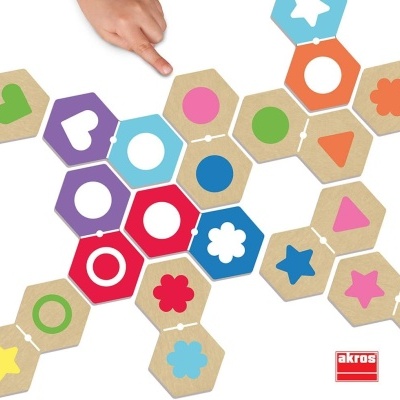 Puzzle de peças hexagonais com formas coloridas e mão a apontar para peça