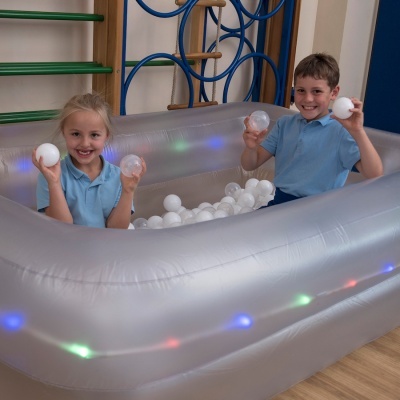 Piscina insuflável transparente com luzes LED e bolas brancas com duas crianças dentro