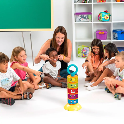 Crianças e mulher jogando com brinquedo empilhável colorido em círculo