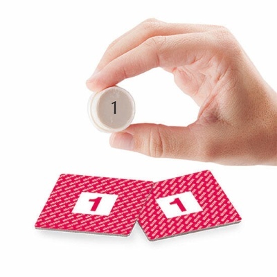 Mão segurando ficha branca com número 1 e duas cartas vermelhas de costas com número 1