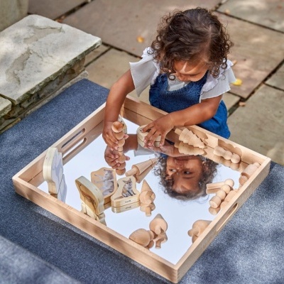 Criança brinca com tabuleiro espelhado e peças de madeira