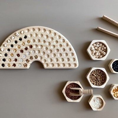 Jogo de mancala de madeira com pedras coloridas e recipientes hexagonais