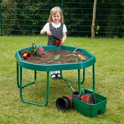 Mesa de jardim infantil com terra, vasos e ferramentas de jardinagem ao ar livre