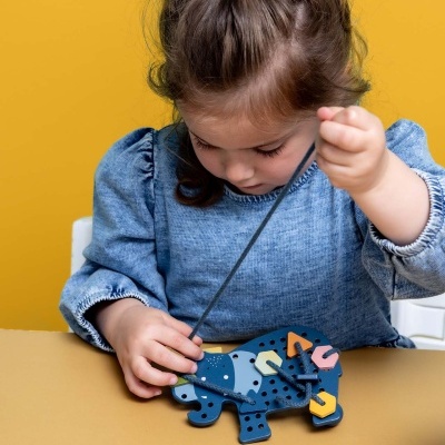 Criança a brincar com brinquedo de madeira azul em forma de rinoceronte