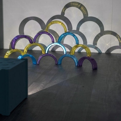 Arcos semicirculares coloridos e transparentes numa superfície escura com sombras projetadas.