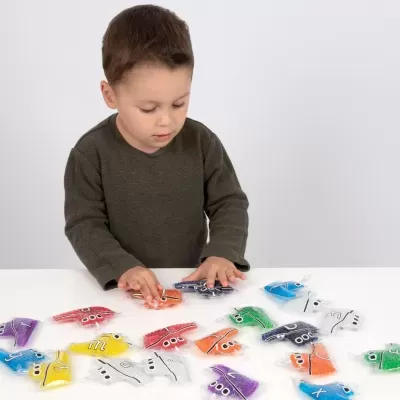 Criança a brincar com letras coloridas de plástico à mesa branca